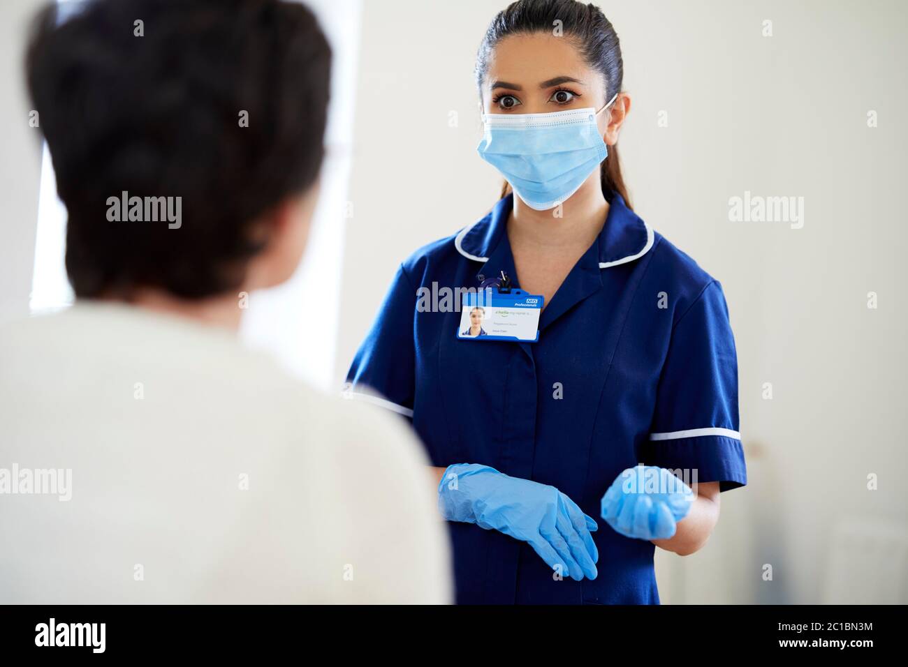 Infirmière parlant au patient portant un EPI Banque D'Images