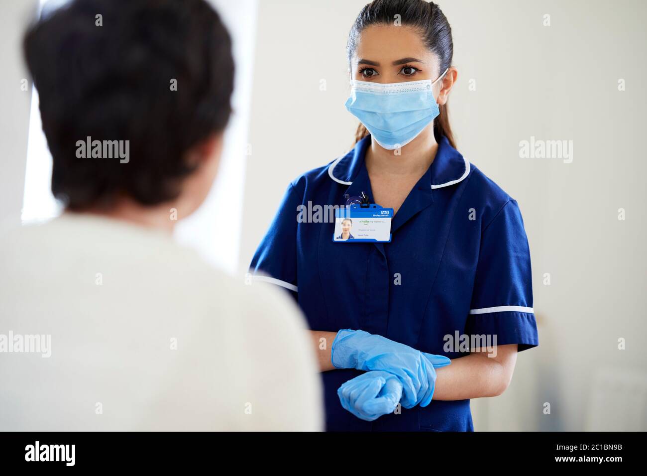 Infirmière portant un masque et des gants d'EPI pour parler au patient Banque D'Images