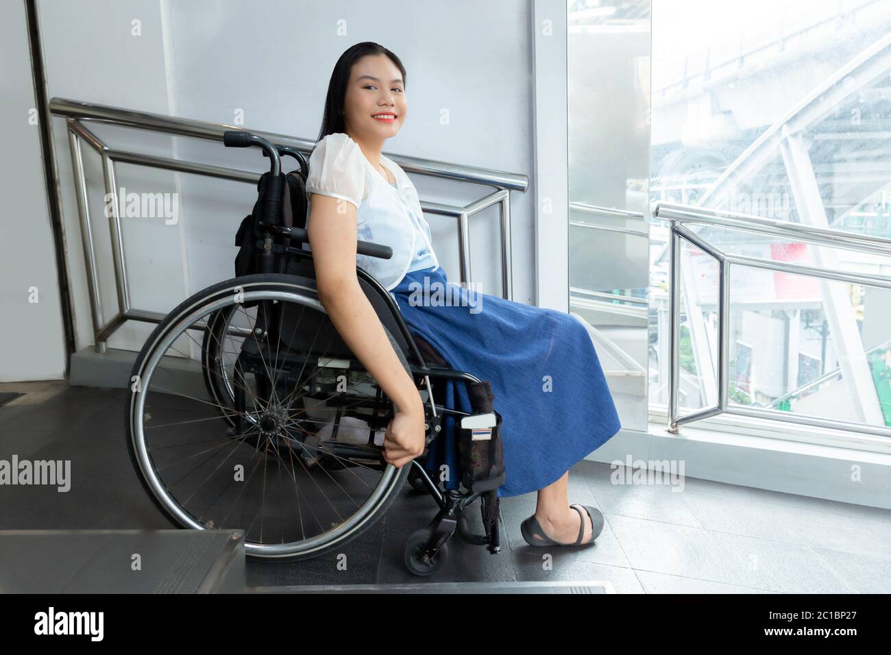 Jeune femme handicapée en fauteuil roulant près de la passerelle de transport handicapés concept de commodité pour les personnes handicapées. Banque D'Images