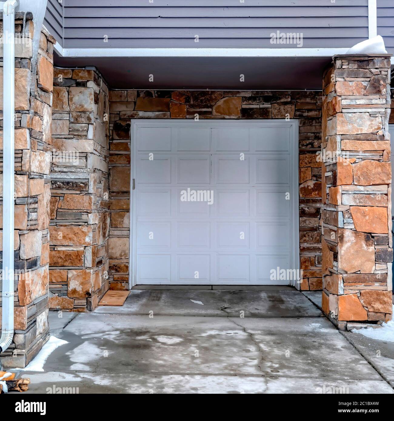 Porte de garage carrée blanche lambrissée avec parement gris et mur  extérieur en pierre Photo Stock - Alamy
