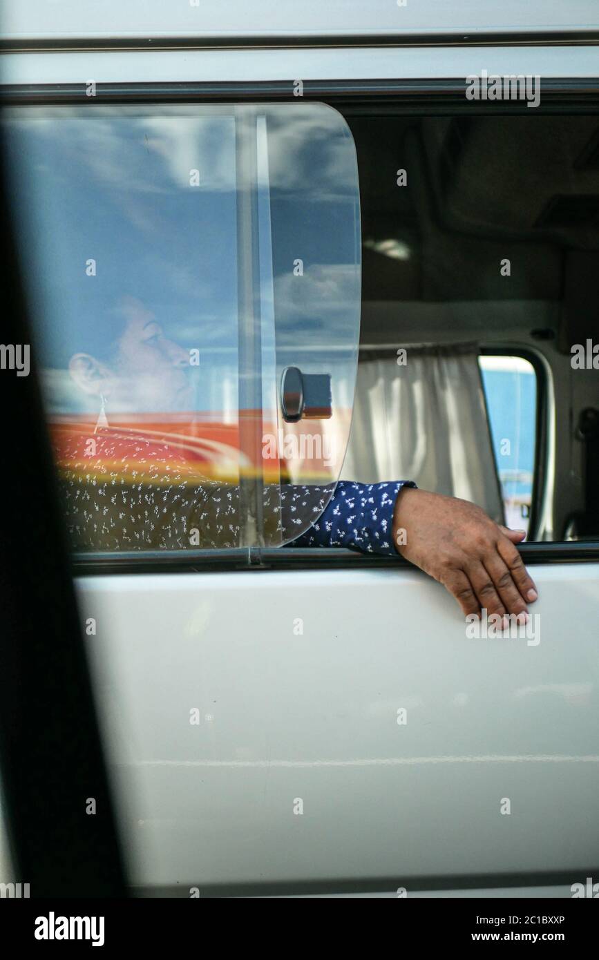 La femme assise dans le bus local avec sa main suspendue à l'extérieur de la fenêtre ouverte, regardant directement dans la caméra. Banque D'Images