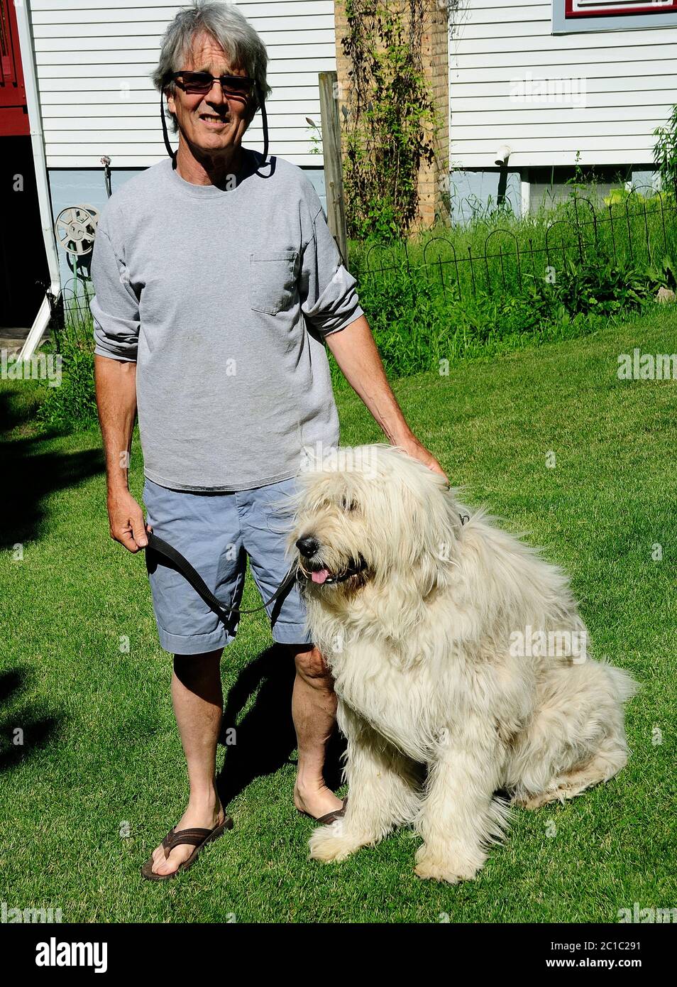 Homme posant dans son arrière-cour avec son chien Chloe qui est partie andalouse Shepard et partie grande Pyranese. Banque D'Images