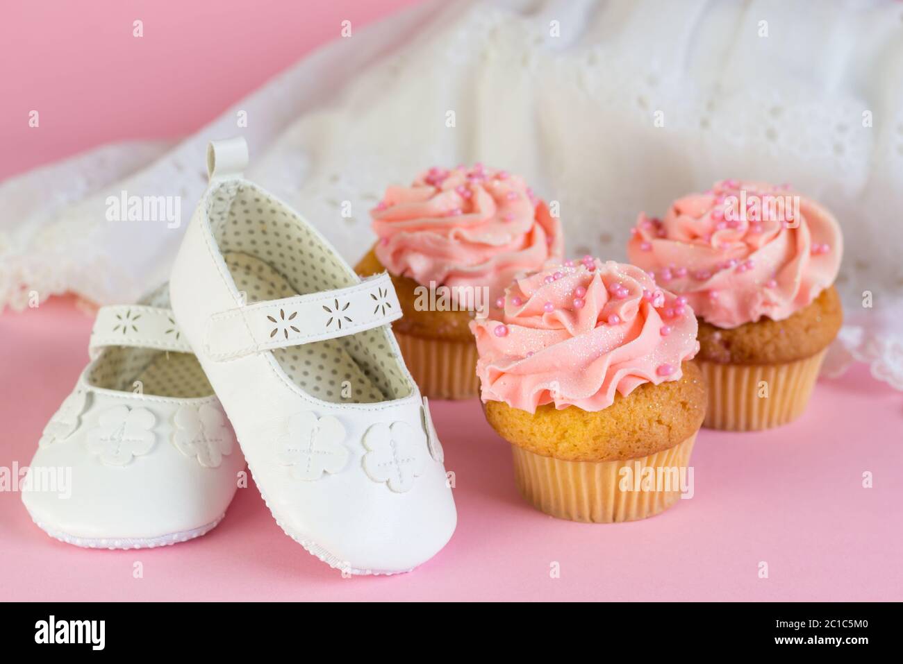 Baptême ou fille d'anniversaire invitation avec gâteaux de tasse rose et blanc chaussures sur fond rose Banque D'Images
