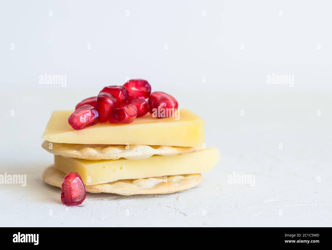 Fromages et craquelins avec pomagranate seeds isolé sur fond blanc rustique Banque D'Images