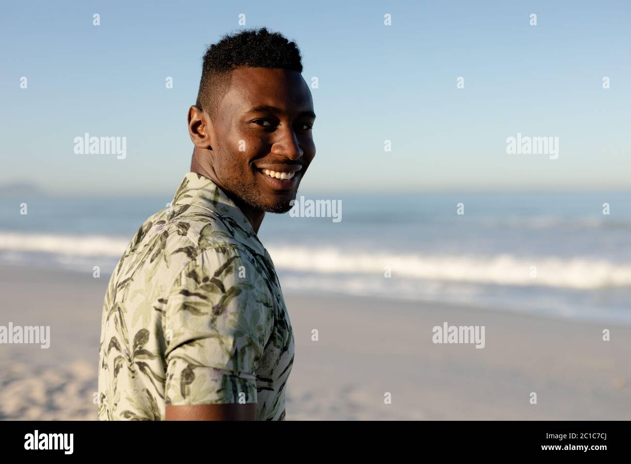 Un homme afro-américain qui profite de temps libre sur la plage par une journée ensoleillée Banque D'Images