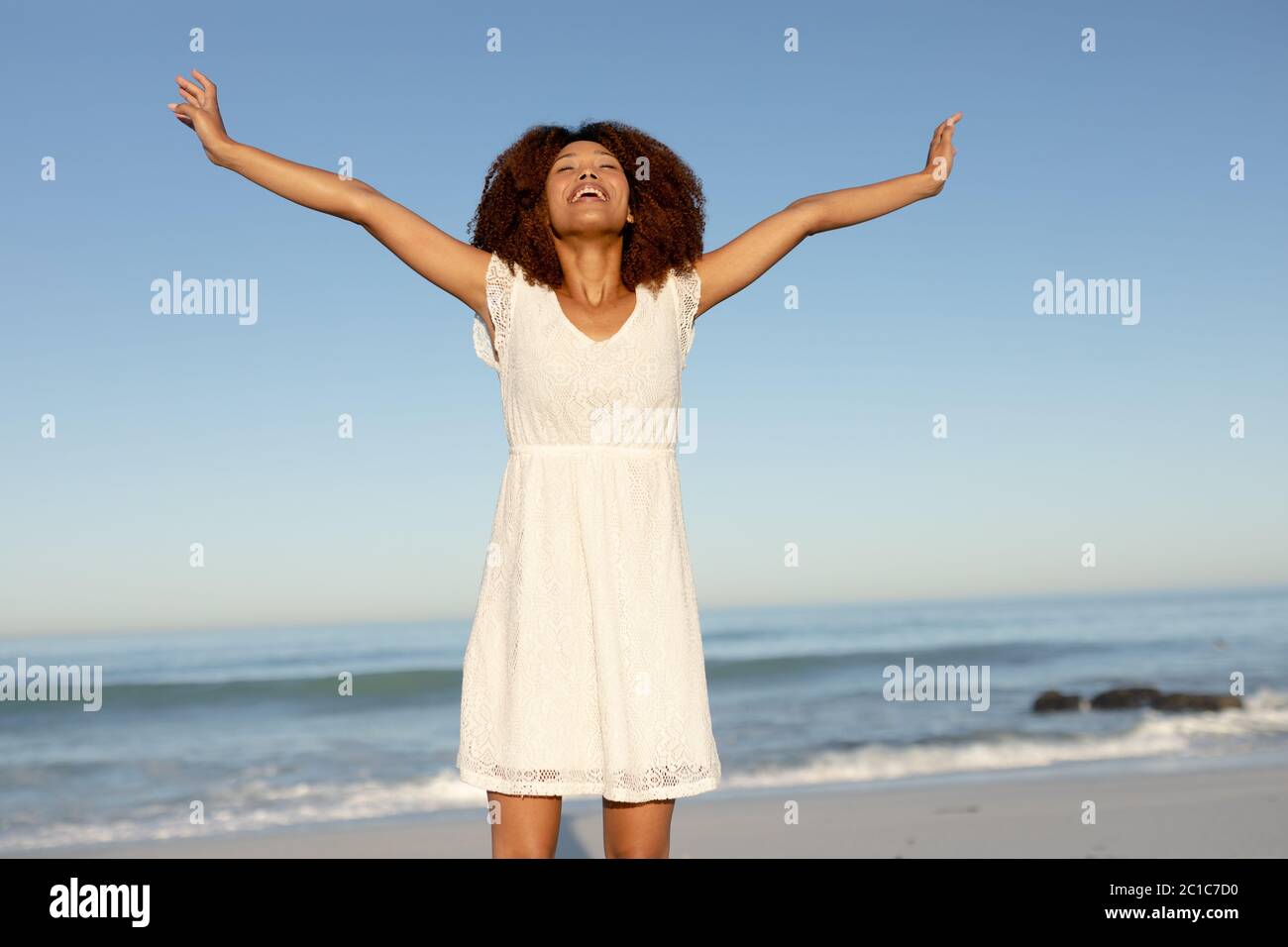 Une femme de course mixte avec ses bras s'étirent sur la plage par un jour ensoleillé Banque D'Images