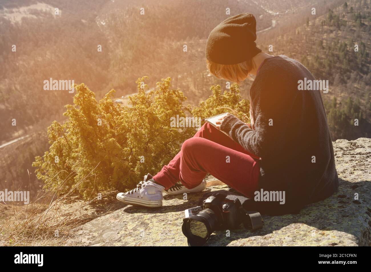 Portrait d'une fille de photographe de couturier hippster en chapeau et  lunettes de soleil dessine un pastel dans son carnet assis sur un rocher en  plein air Photo Stock - Alamy