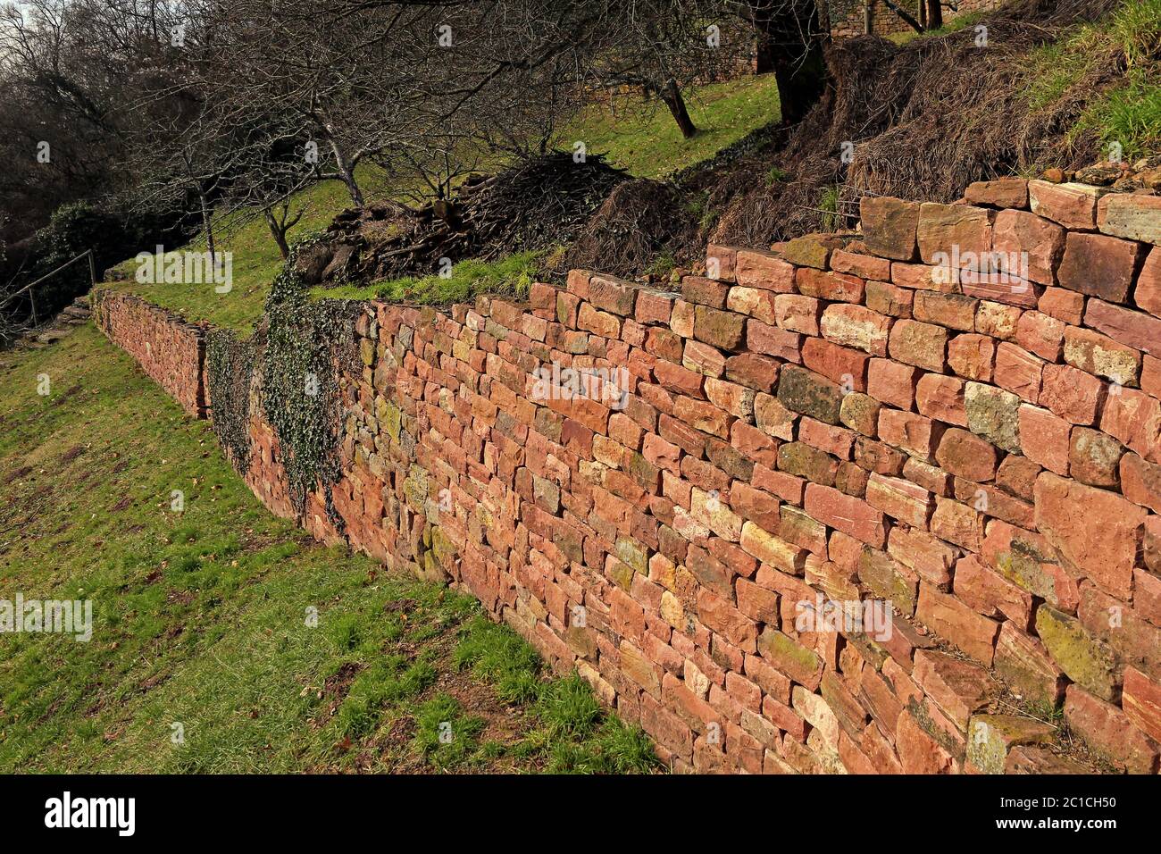 Mur en pierre sèche de grès rouge dans un jardin naturel Banque D'Images