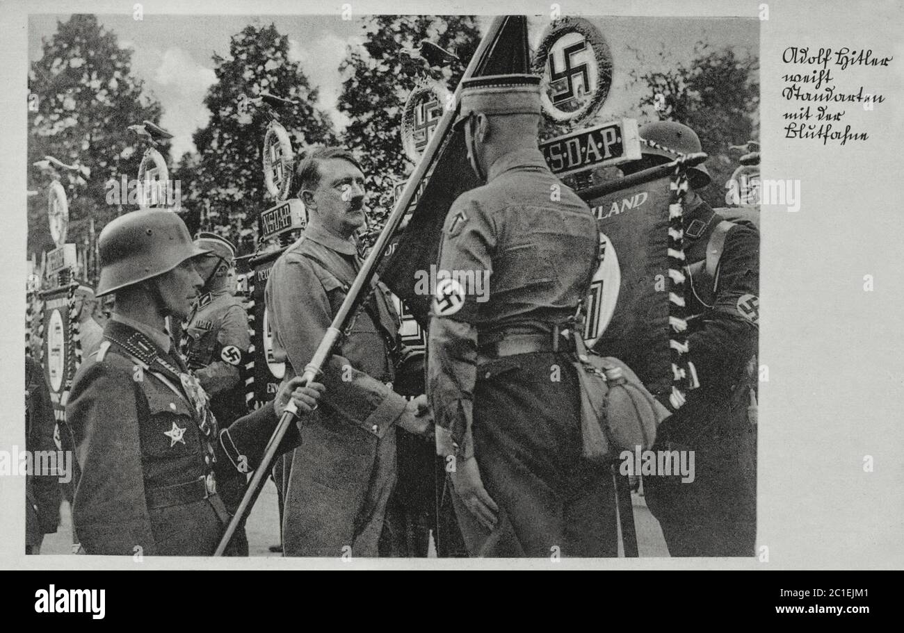 Adolf Hitler Greets les normes avec le drapeau de sang ( drapeau nazi de la Swastika allemande ). Carte postale de propagande allemande. années 1930 Banque D'Images