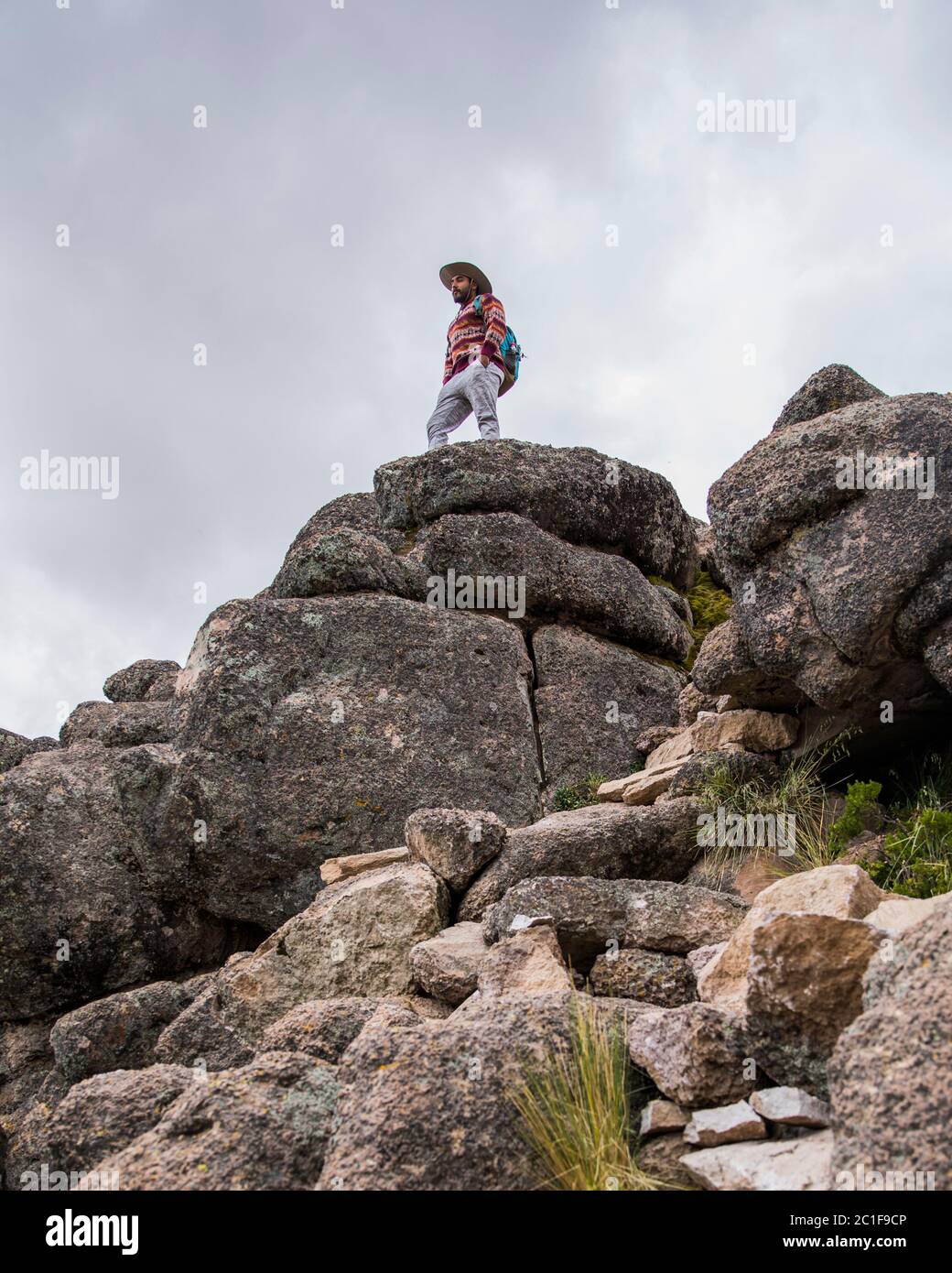 jeune homme debout sur un grand rocher, des rochers et nuageux Banque D'Images