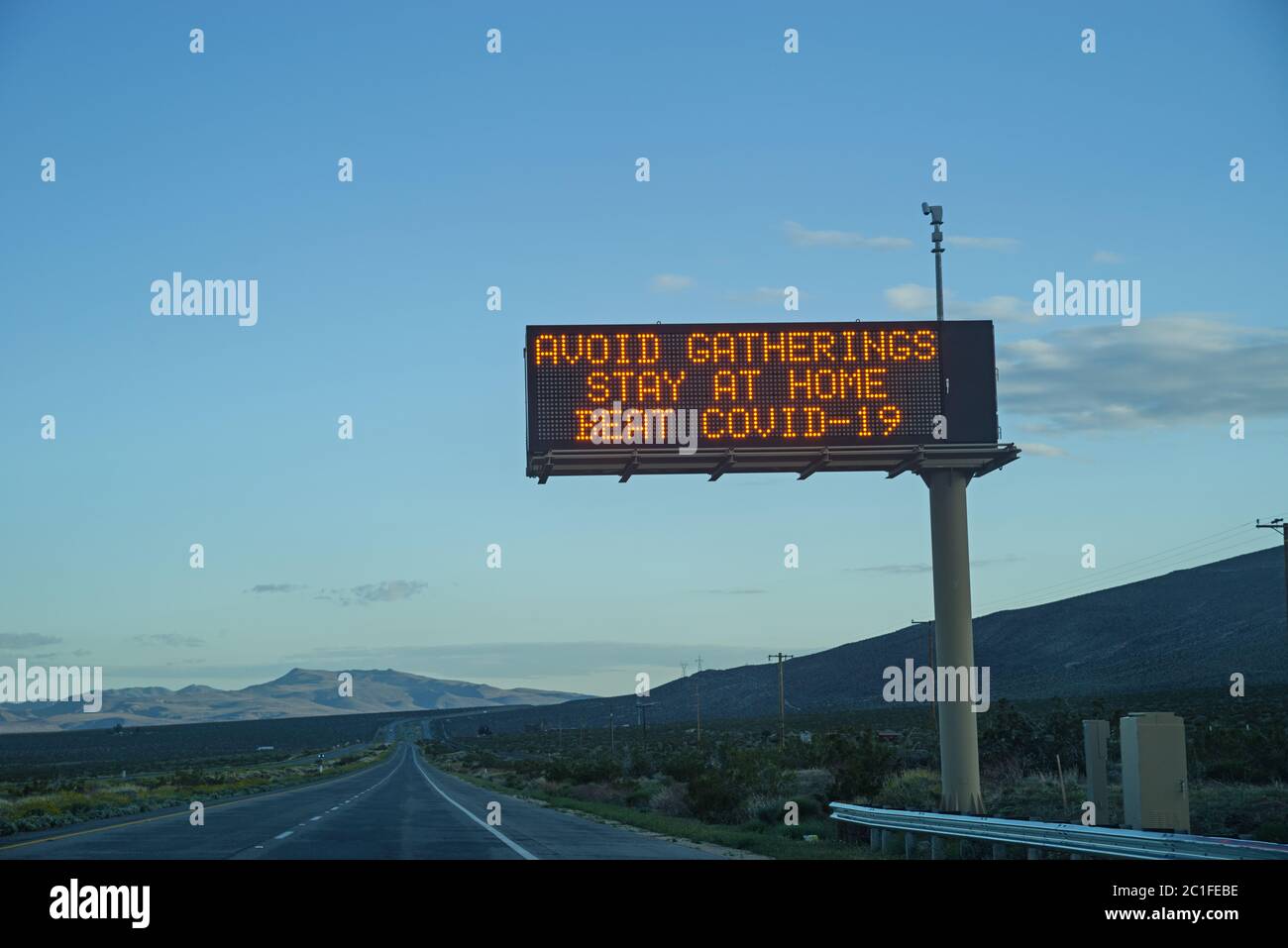Évitez les rassemblements restez à la maison, évitez le panneau de l'autoroute COVID-19 près du crépuscule Banque D'Images