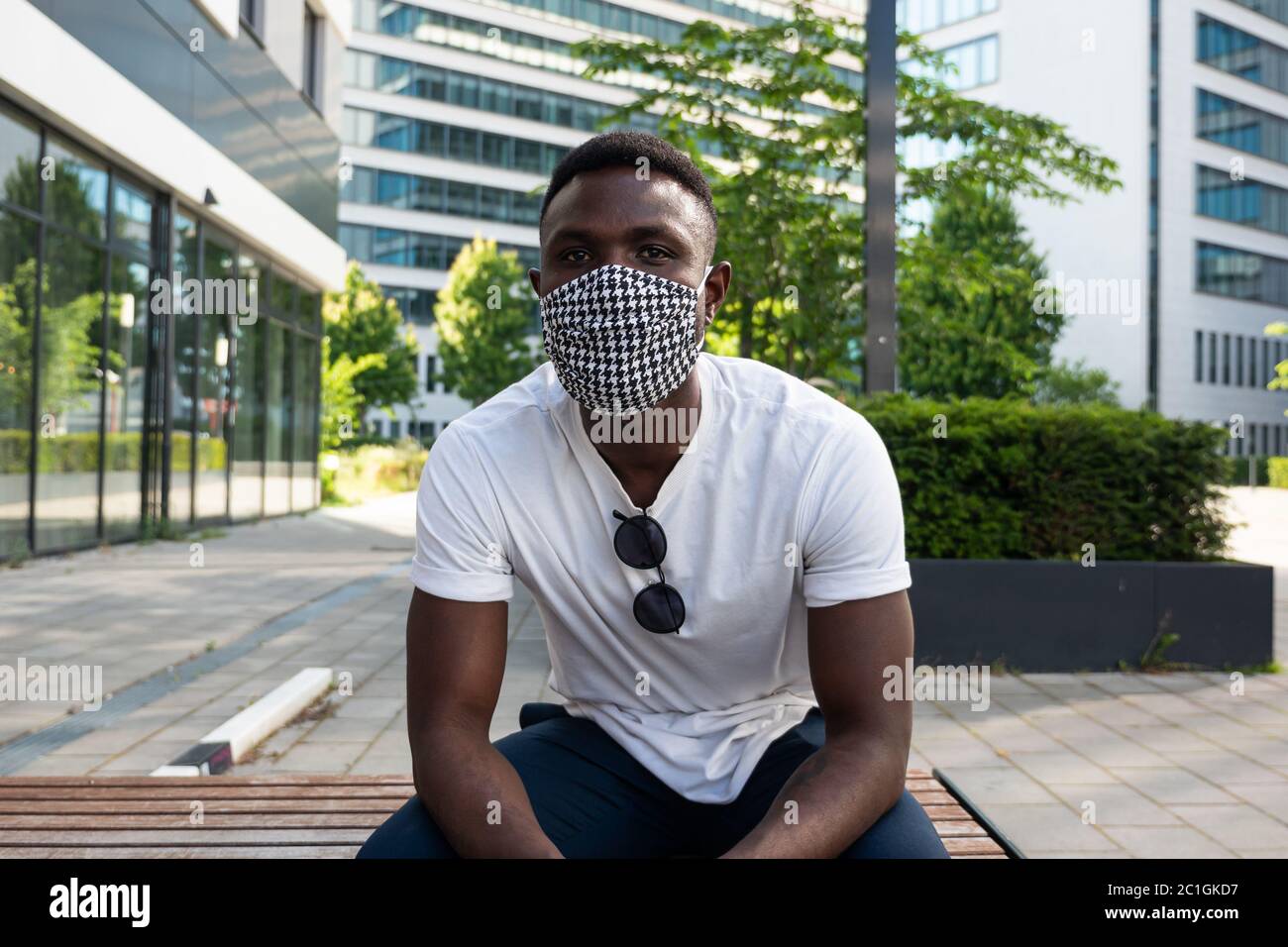 Jeune homme noir portant un masque de visage regardant l'appareil photo. Prise moyenne. Extérieur. Arrière-plan de la ville. Banque D'Images