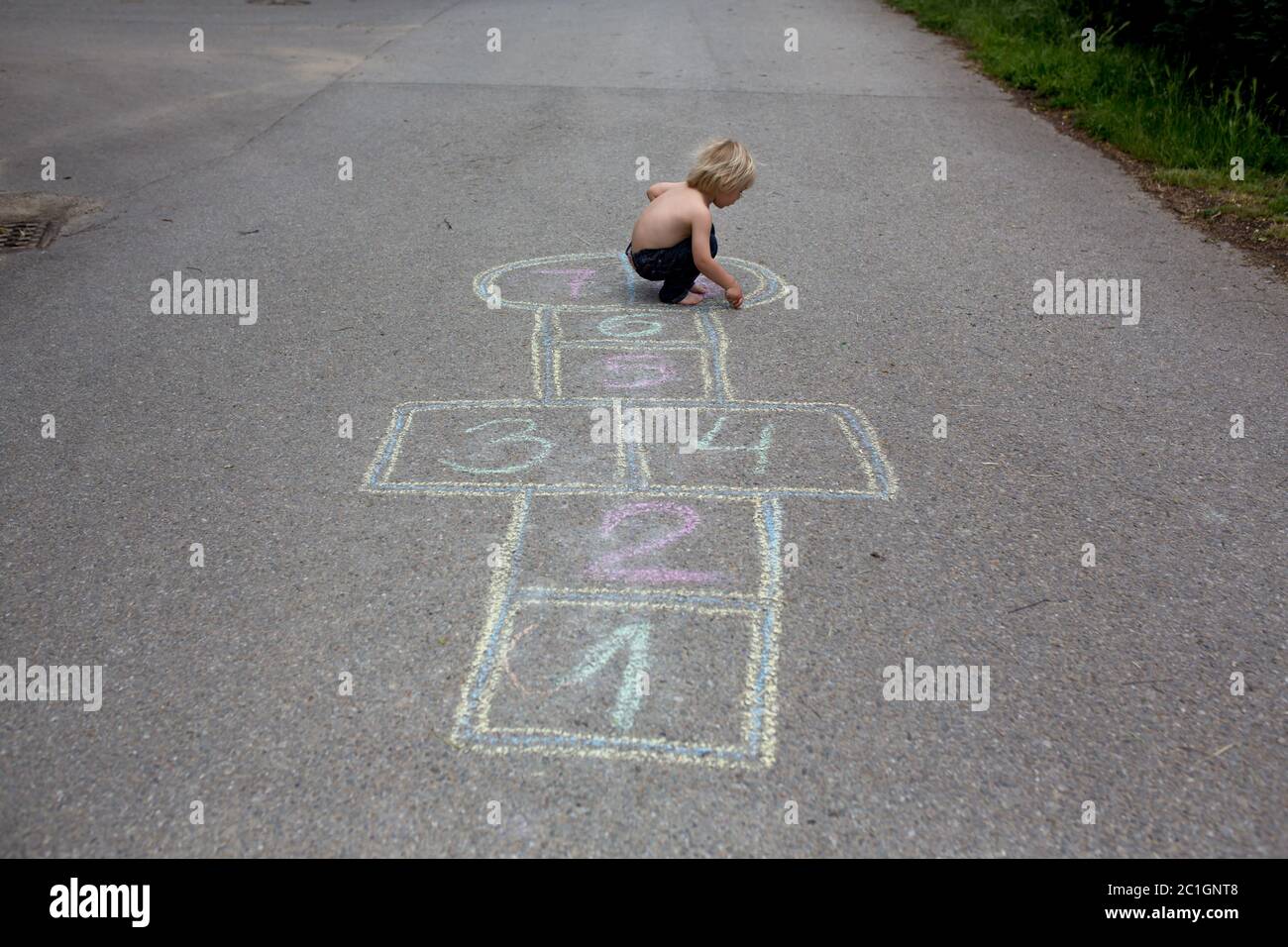 Enfant, blond, jouant au hopscotch dans la rue, l'été Banque D'Images