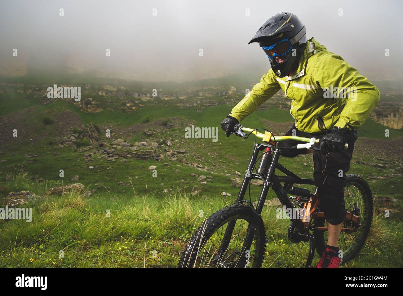 Un homme dans un casque de montagne, à vélo de montagne, fait le tour de la belle nature par temps nuageux. Descente Banque D'Images