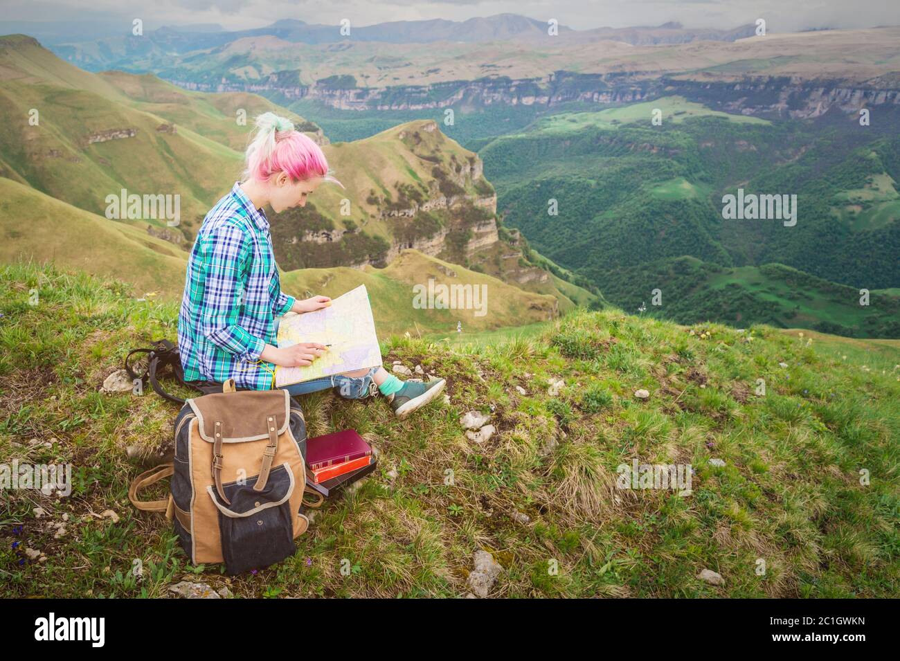 Fille voyageur avec des cheveux multicolores assis sur la carte de lecture de la nature et tenant une boussole à la main. Le concept de navigation Banque D'Images