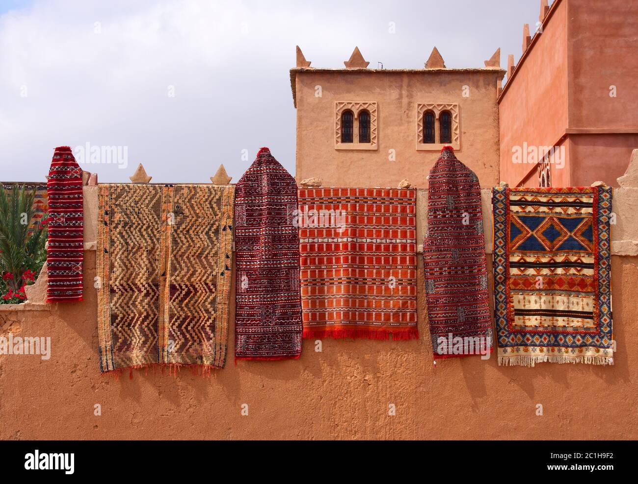 Maroc, Marrakech, tapis berbères marocains colorés typiques suspendus sur un mur en adobe. Banque D'Images