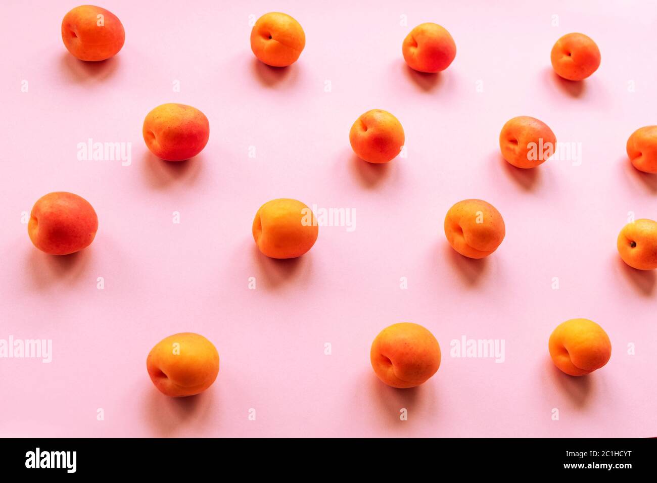 Abricots orange dispersés sur une table rose. Concept de nourriture saine, vue du dessus. Banque D'Images