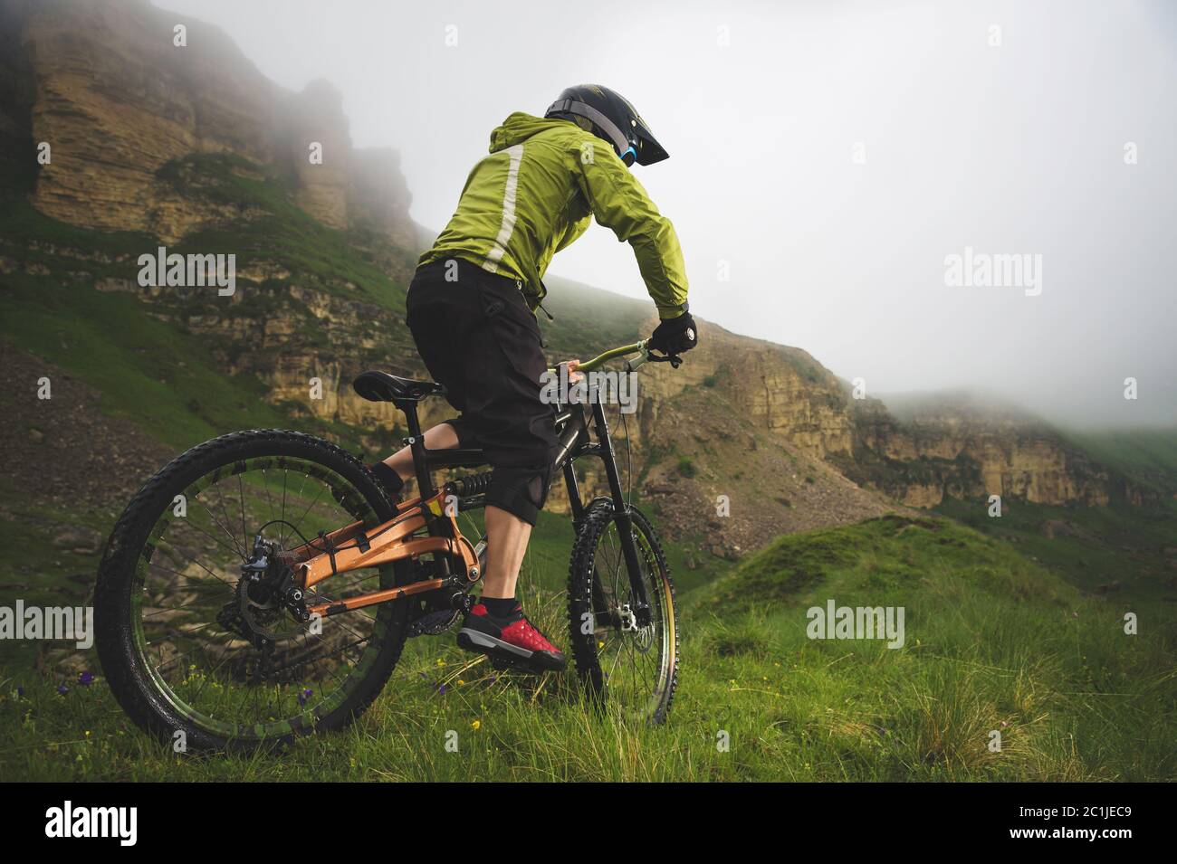 Un homme dans un casque de montagne, à vélo de montagne, fait le tour de la belle nature par temps nuageux. Descente Banque D'Images