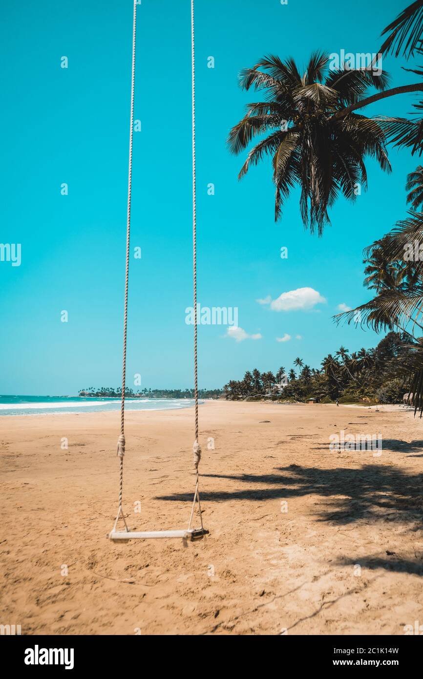 Balançoire à corde abandonnée pendant l'isolement social lors d'une journée ensoleillée à la plage. Ciel bleu vif en arrière-plan. Balancement vide et personne autour Banque D'Images