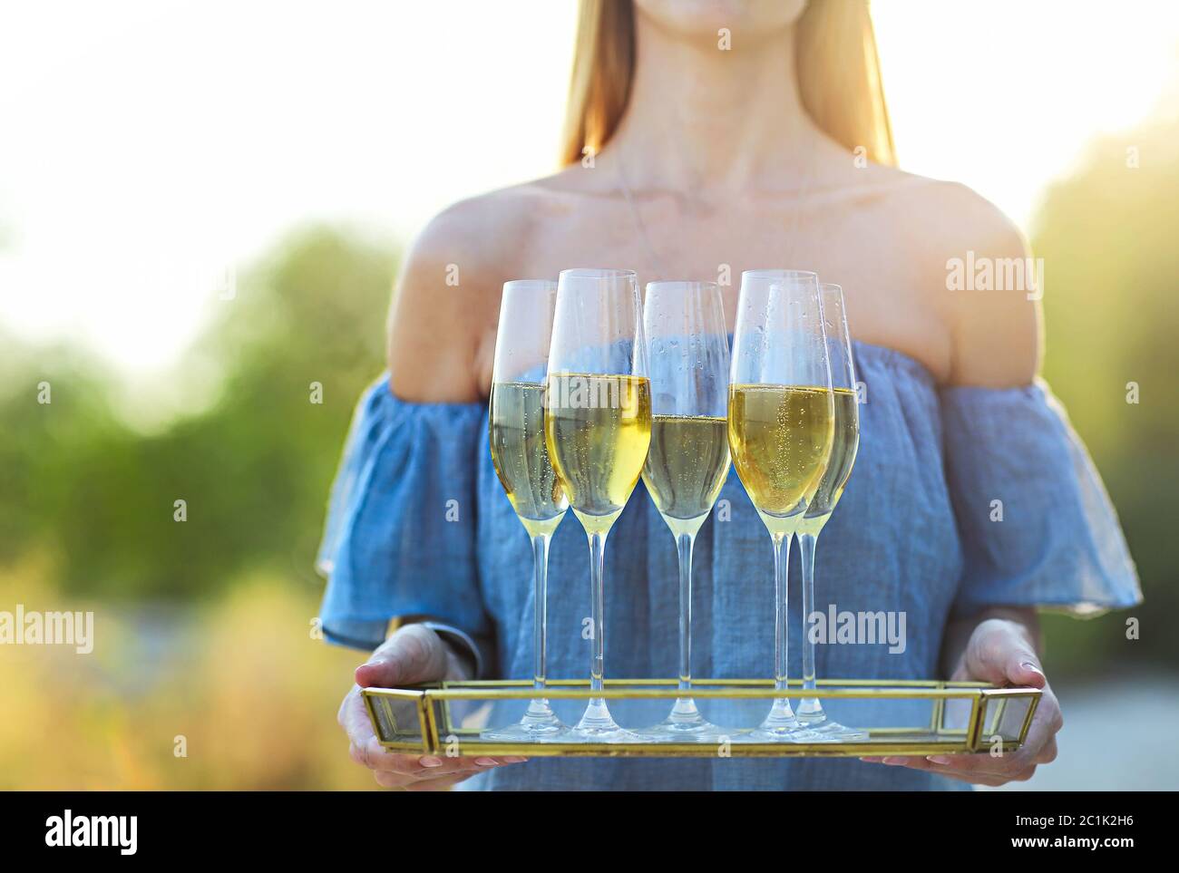Bonne femme tenant un plateau avec du champagne vin mousseux dans des verres à l'extérieur sur une plage Banque D'Images