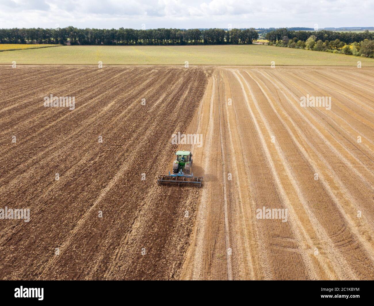 Les travaux préparatoires pour l'ensemencement des cultures, la culture du sol par un tracteur après la récolte en été. Banque D'Images