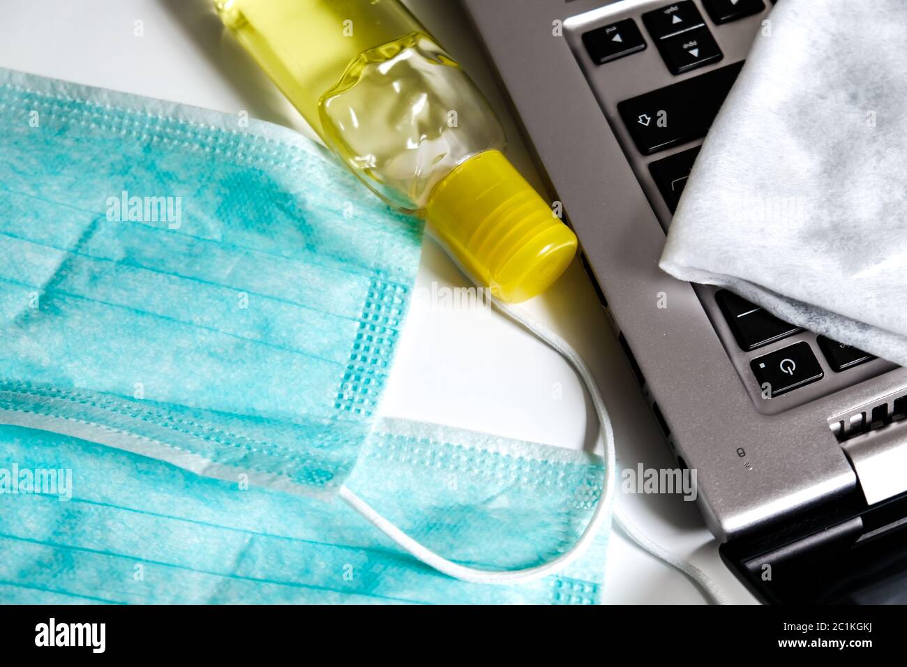 Les essentiels de prévention des virus : masques pour le visage, bouteille jaune de désinfectant pour les mains et serviette pour nettoyer un ordinateur portable. Étude à domicile ou environnement de travail isolé Banque D'Images