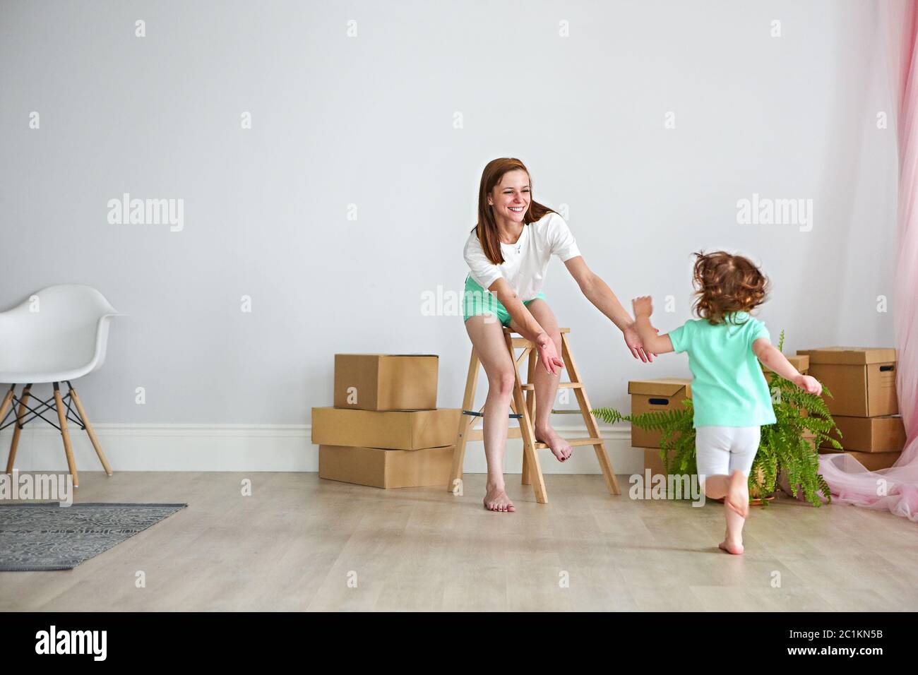 Une famille heureuse qui joue dans une nouvelle maison. Mère et fille s'amusant ensemble Banque D'Images