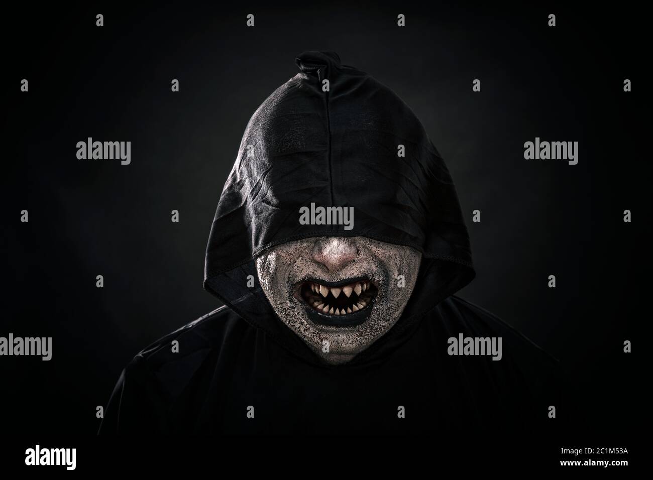 La figure effrayante dans hooded cloak montrant ses dents pointues sharp Banque D'Images