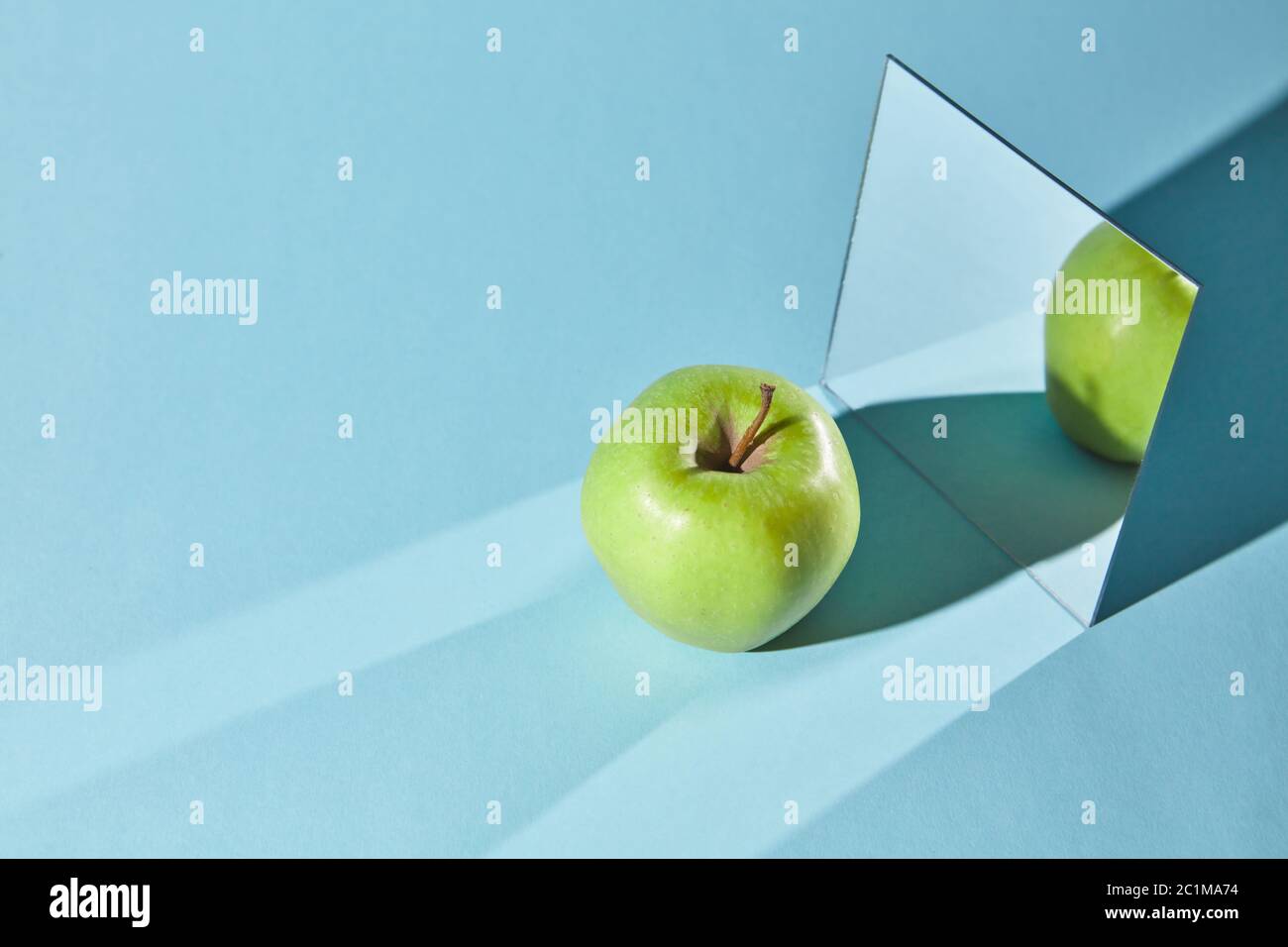 La pomme est verte, un miroir carré sur fond bleu, un reflet d'une pomme et  des ombres dans un miroir Photo Stock - Alamy