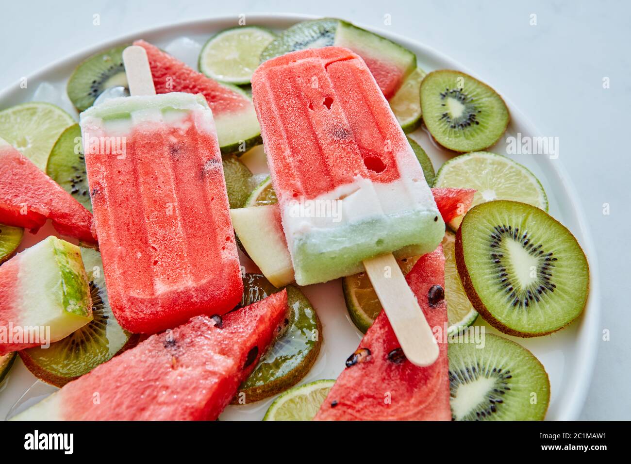 Dessert d'été de jus de fruits surgelés, lally avec glace et morceaux de  pastèque, kiwi et citron vert dans une assiette sur un fond de marbre gris  Photo Stock - Alamy