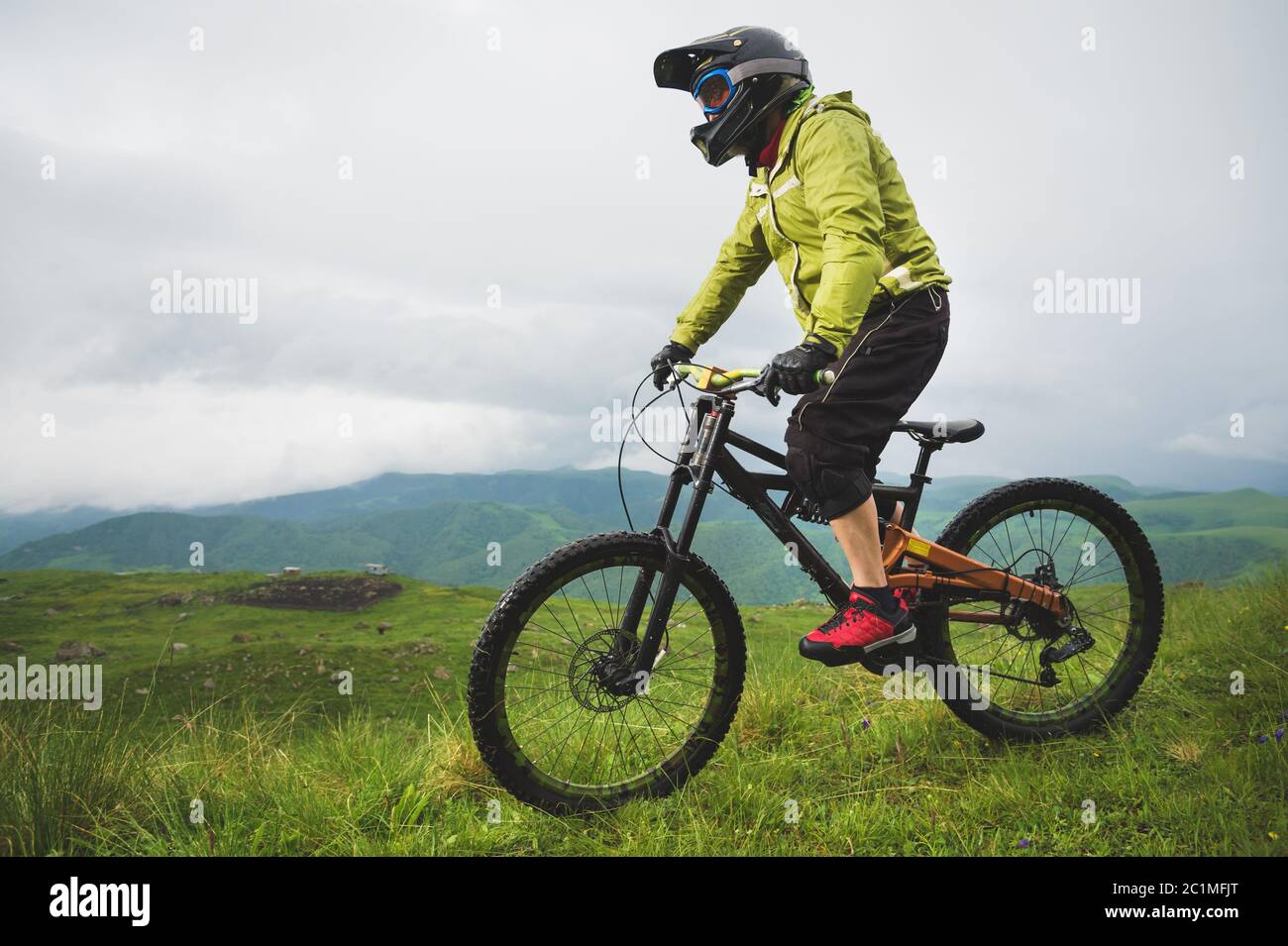 Un homme dans un casque de montagne, à vélo de montagne, fait le tour de la belle nature par temps nuageux. Descente Banque D'Images
