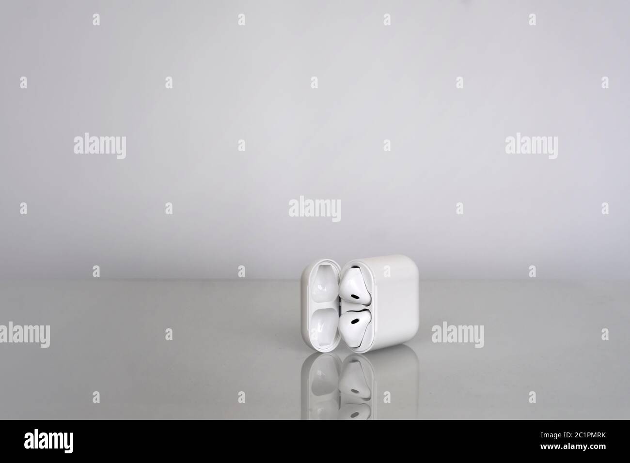 Écouteurs sans fil avec boîtier de chargement sur fond gris avec réflexion dans le verre Banque D'Images