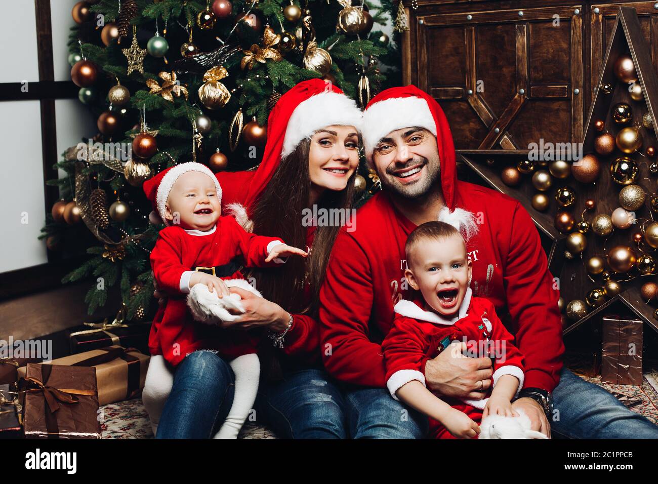 Famille heureuse avec deux adorables enfants s'amusant à l'arbre de Noël. Banque D'Images