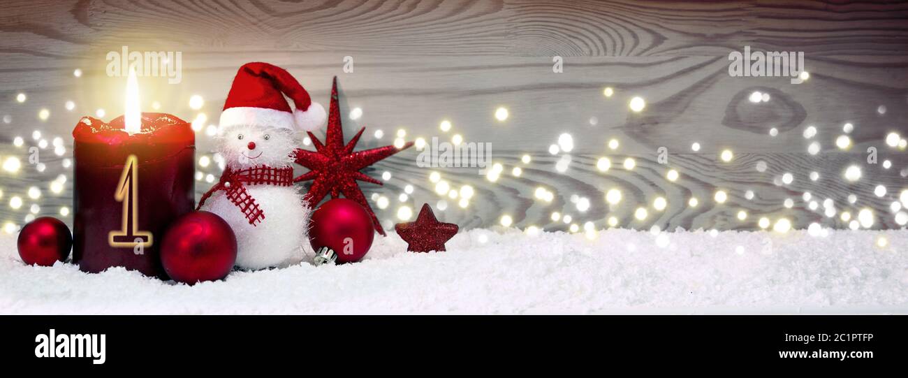 Fond de Noël avec première bougie de l'Avent et bonhomme de neige avec décoration rouge. Banque D'Images