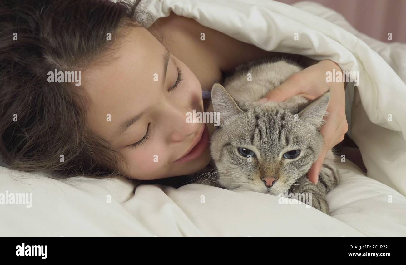 Happy teen girl baisers et des pourparlers avec Thai cat in bed Banque D'Images