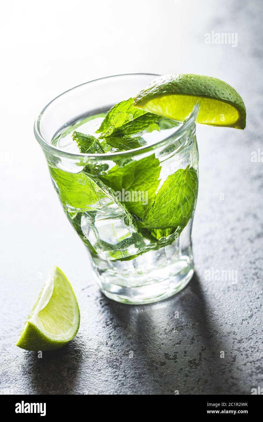 Cocktail avec du citron vert, de la menthe et des glaçons sur une table noire. Banque D'Images