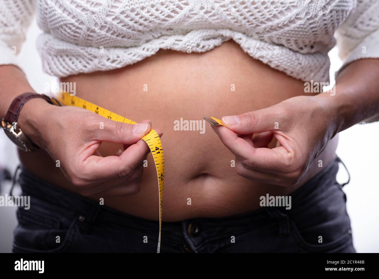 Portrait Woman Measuring son ventre jaune avec un ruban à mesurer Banque D'Images