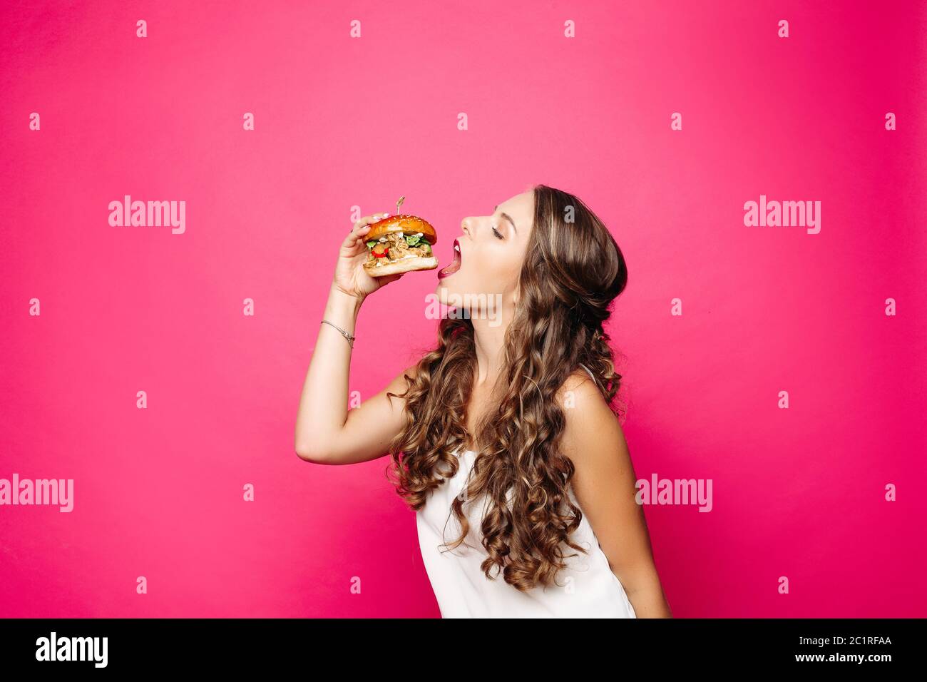 Fille avec faim manger la bouche ouverte grande hamburger. Banque D'Images