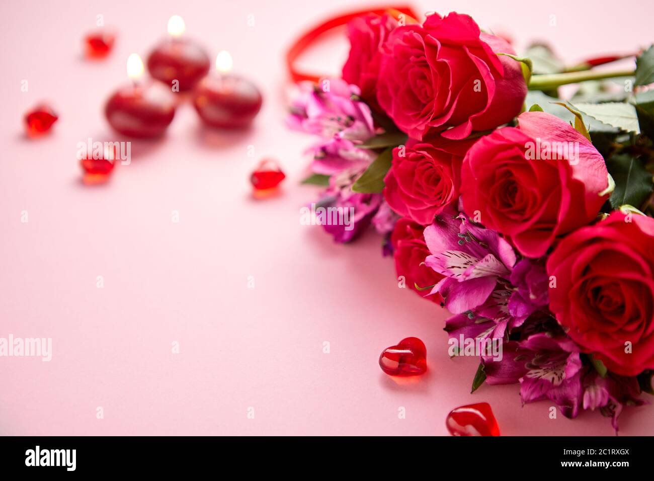 Bouquet de fleurs mixtes avec des roses, des bougies en forme de cœur et des décorations en acrylique Banque D'Images