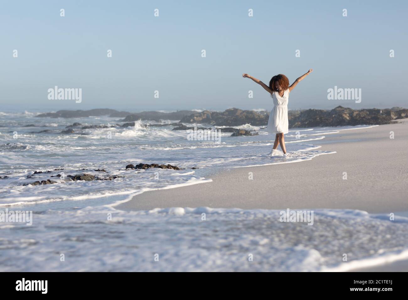 Une femme de course mixte avec ses bras s'étirent sur la plage par un jour ensoleillé Banque D'Images