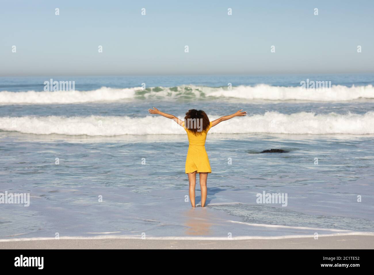 Une femme de course mixte avec ses bras s'étirent sur la plage par un jour ensoleillé Banque D'Images