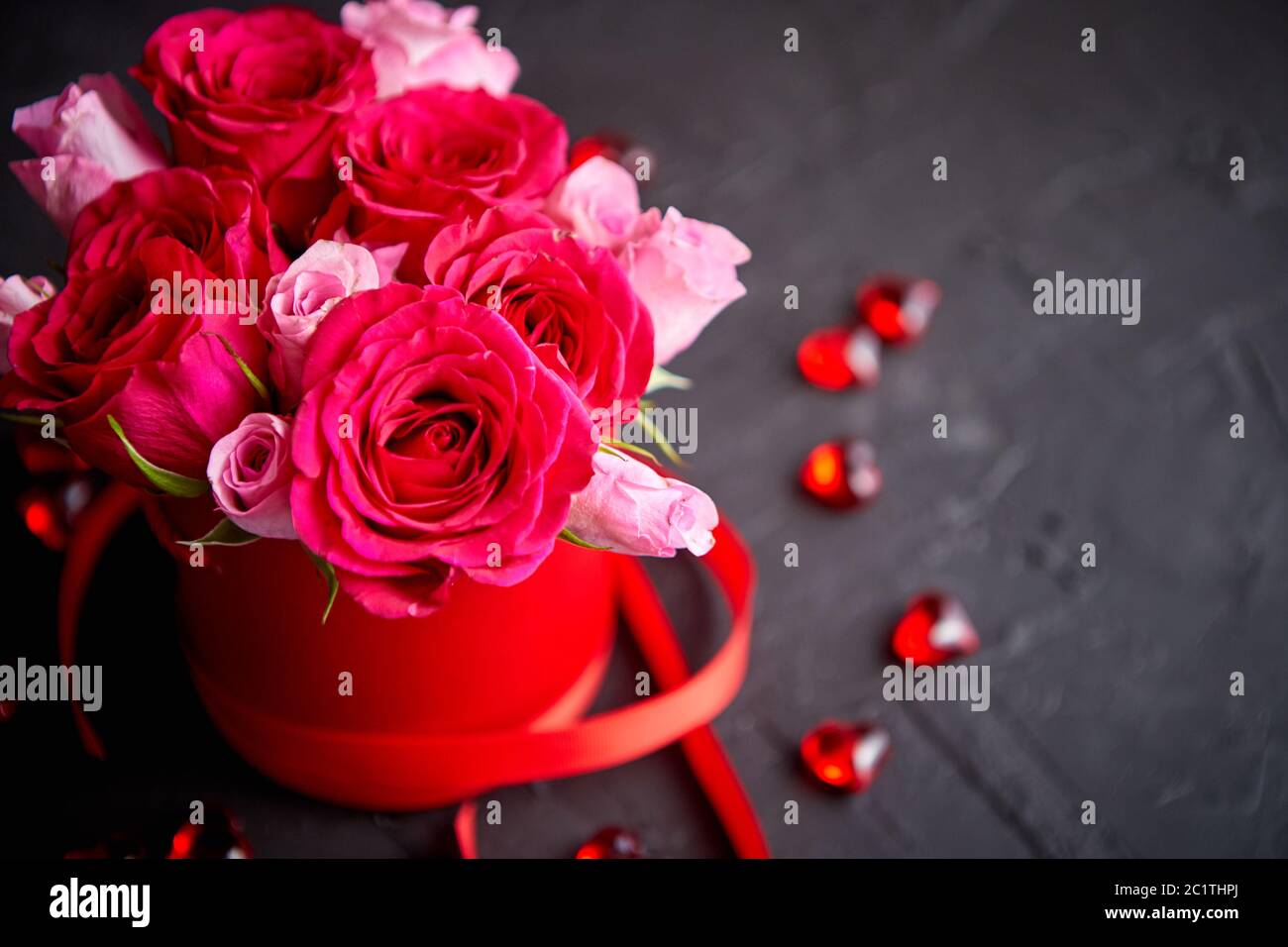 Bouquet de roses roses emballées en boîte rouge et noir sur fond de pierre Banque D'Images