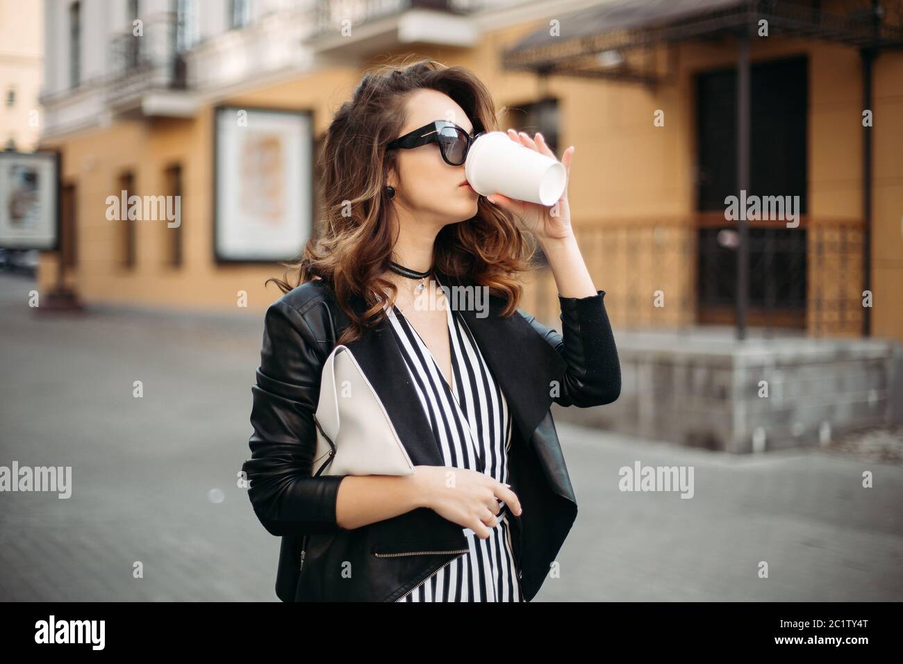 Swag brunette fille de boire du café dans la rue. Banque D'Images