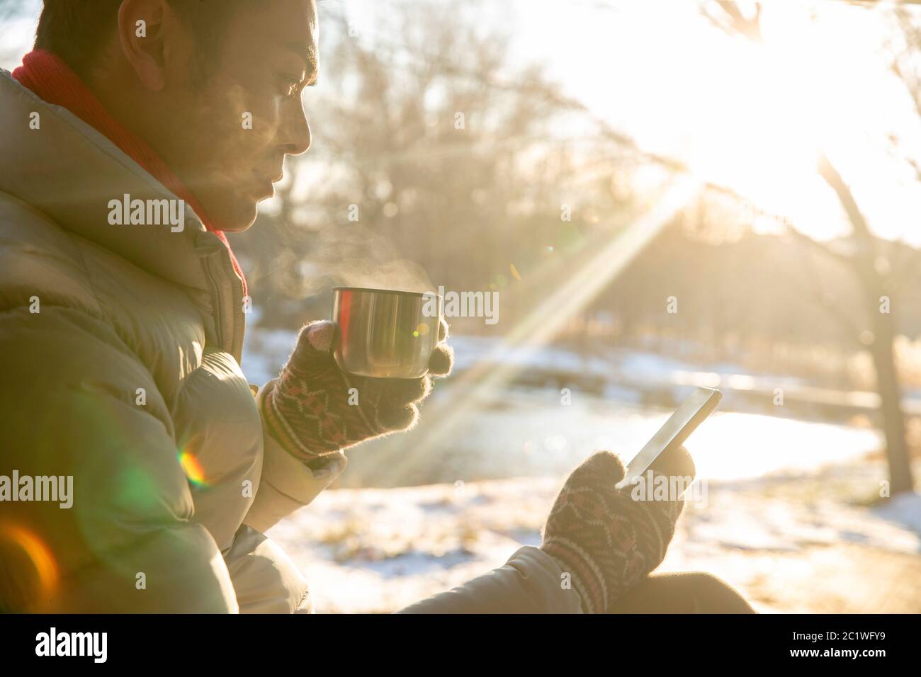L'homme assis dans la neige pour voir le téléphone portable Banque D'Images