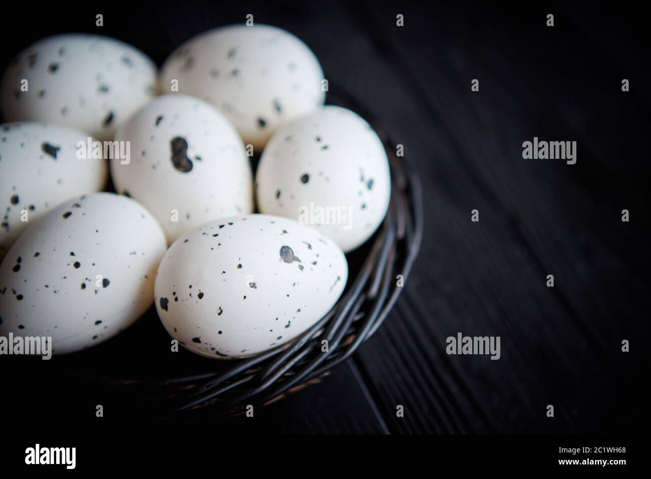 Poulet entier oeufs dans un nid sur un fond rustique en bois noir. Les symboles de Pâques Banque D'Images