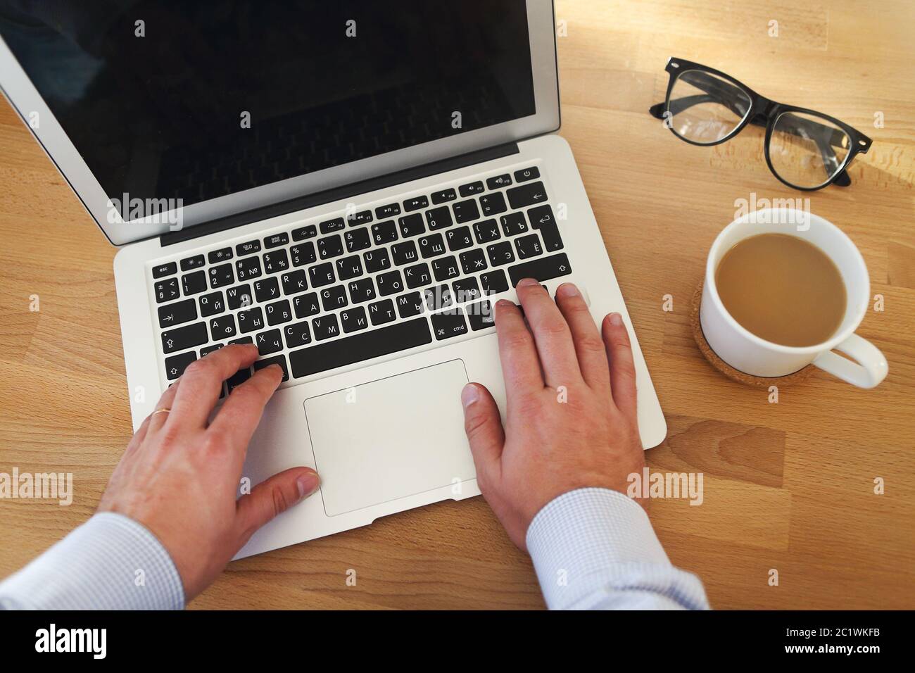 Vue de dessus d'un homme travaillant sur un ordinateur portable et prenant une tasse de café Banque D'Images
