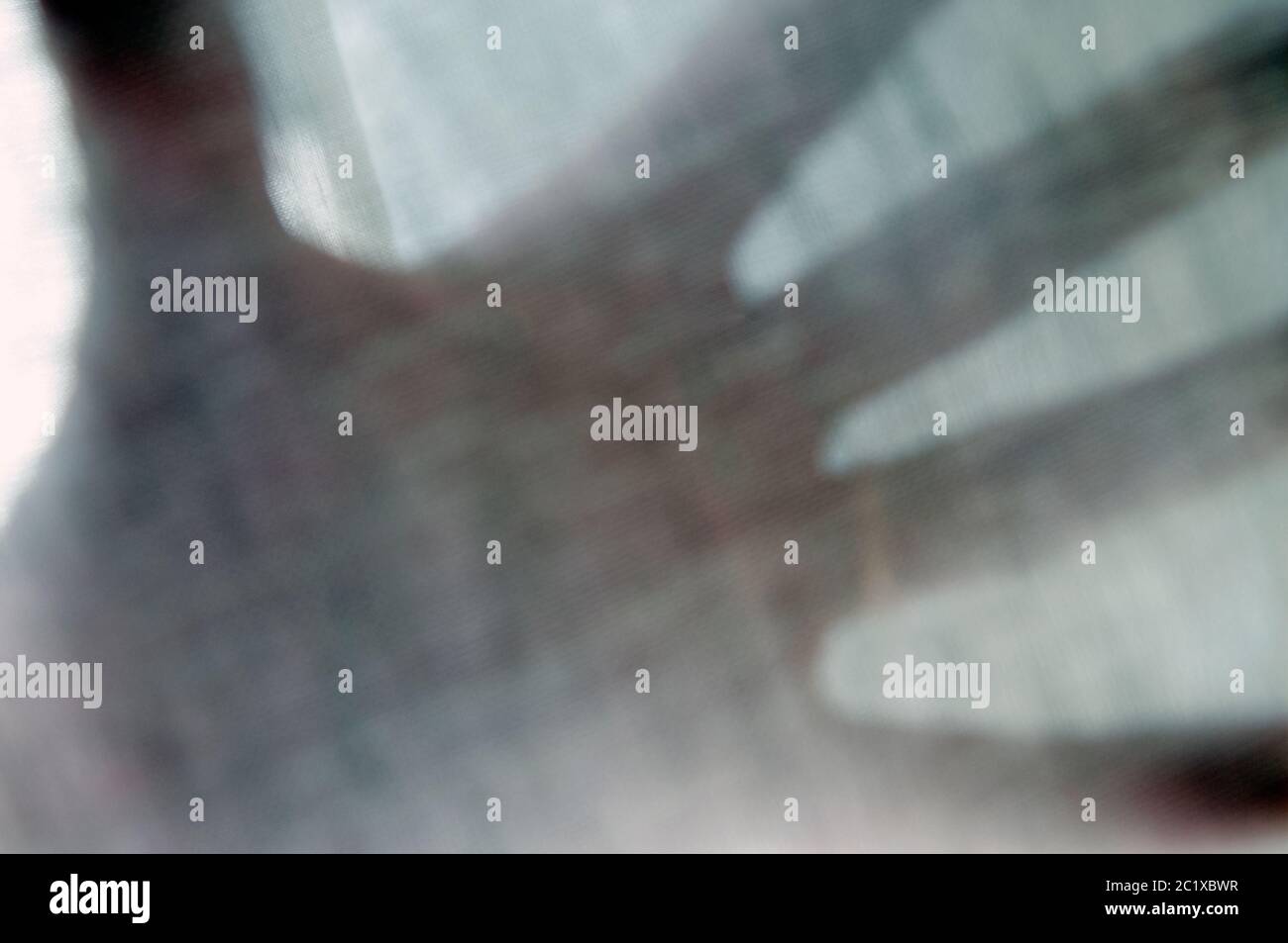 Une image floue de gros plan de la paume d'UNE main vue à travers UN rideau de mousseline Banque D'Images