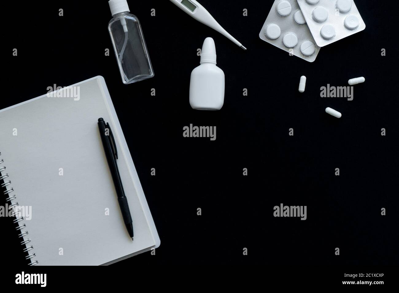 vue de dessus du thermomètre, des pilules et du carnet sur fond noir Banque D'Images
