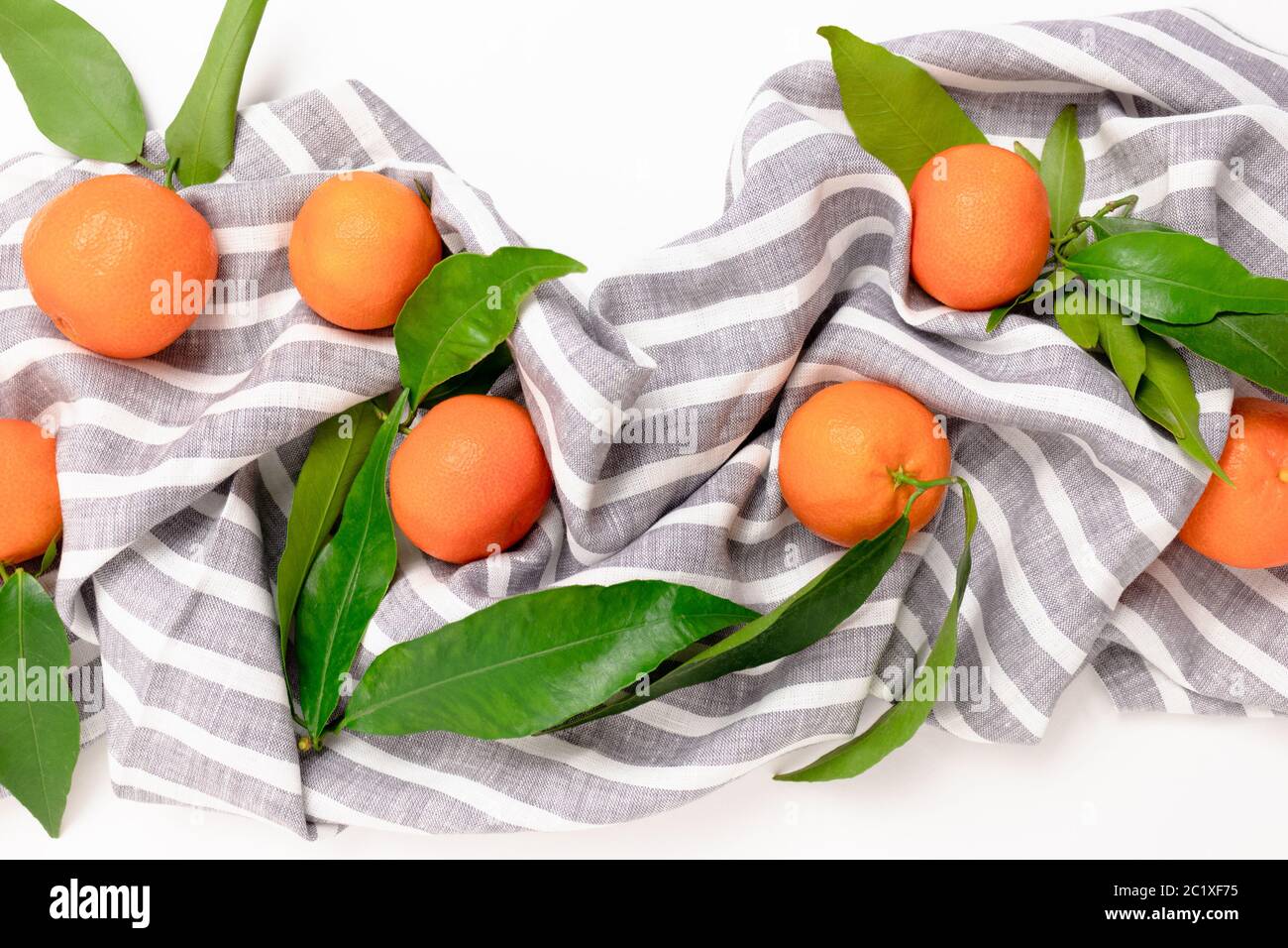Mandarines sur une serviette en lin rayée sur fond blanc Banque D'Images
