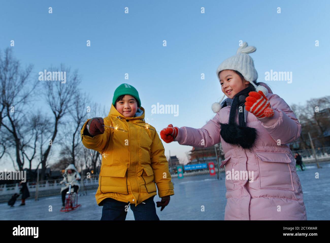 Les enfants sont heureux de faire du patinage sur la patinoire des feux d'artifice Banque D'Images